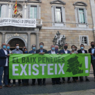 Plano abierto de los 14 alcaldes del Baix Penedès mostrando una pancarta delante del Palau de la Generalitat.