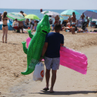 Un chico que se dirige a la playa de Salou (Tarragonès) con dos flotadores.