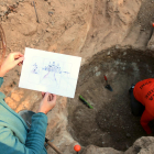 La doctora en Prehistoria, Georgina Prats, mostrando un dibujo del uso de uno de los silos descubiertos al yacimiento Mas Cap del Ferro, en Nulles.