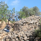 La investigadora Cèlia Mallafrè prenent mides d'una construcció de pedra en sec.