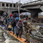 Soldados ucranianos ayudan a la población a superar un puente destruido para acceder a Kyiv.