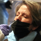 Una dona amb els ulls tancats mentre li extreuen una mostra de PCR.