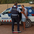 Un mosso se lleva a uno de los detenidos.