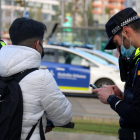 Un usuario de patinete eléctrico, parado durante un control de la Guardia Urbana de Barcelona, ante la Torre Glorias, mientras un agente lo identifica.