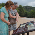 Dos mujeres leen el panel informativo instalado en el Mas de Santa Magdalena, en Móra d'Ebre.