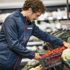 Un treballador de supermercat col·locant bé la secció de verdures.