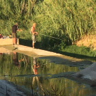 Varias personas con caña pescando el río.