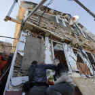 Varias personas tratan de arreglar parte de los numerosos desperfectos causados tras el impacto de varios proyectiles en una zona residencial de Odesa