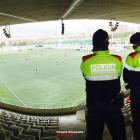 Dos mossos vigilant durant un partit de futbol.