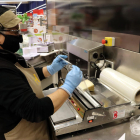 Una treballadora embolica un formatge amb un paper film compostable.