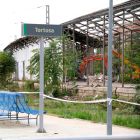 Un cartel de Tortosa de la estación de tren frente a las máquinas trabajando al fondo en el derribo de los antiguos almacenes.