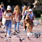Unes turistes passegen entre coloms a la plaça de Catalunya de Barcelona, l'11 d'octubre del 2021.