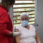 Una profesional sanitaria prepara el brazo de la paciente antes de vacunarla.
