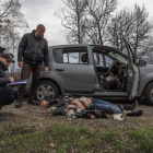 Policies al costat de la dona assassinada estirada a terra al costat d'un cotxe, a Butxa.