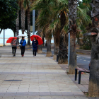 Tres mujeres pasean con paraguas por el paseo marítimo de Cambrils.