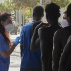 Dos sanitarias atienden a decenas de inmigrantes han entrado este viernes en Melilla tras romper la puerta de acceso al paso fronterizo de Barrio Chino