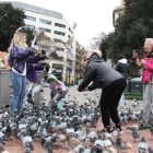 Unes turistes interactuen amb els coloms de Plaça Catalunya mentre es fan fotos.