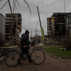 Un hombre camina con su bicicleta frente a un edificio que sufrió daños tras un ataque con artillería pesada, hoy, en Borodianka (Ucrania