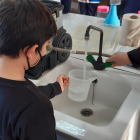 Un nen omple un recipient d'aigua en una taller experimental.