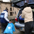 Dos personas refugiadas de Ucrania que viven en Osona sacan bolsas del coche.