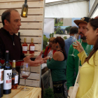 Una chica, con una copa en la mano, escuchando las explicaciones del responsable de una bodega en la Feria del 2019.