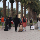 Un grup de persones amb maletes caminant pel passeig Jaume I de Salou.