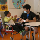 Un treballador li dona el dinar a un nen amb discapacitat en un centre de Sant Gregori.