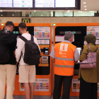 Diverses persones a les màquines d'autovenda de Rodalies de l'estació de Sants.