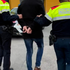 Dos agents dels Mossos d'Esquadra traslladant un dels detinguts.