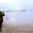 Un hombre toma imágenes del acceso a la barra del Trabucador inundado por el mar.