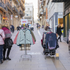 Gent mirant els productes de les paradetes de les botigues del Carrer Sant Agustí.