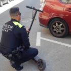 Un agente de la Guardia Urbana de Reus examina un patinete eléctrico.