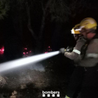 Dos bombers durant les tasques d'extinció de l'incendi en un barranc de