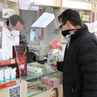 Pla conjunt d'un usuari comprant quatre tests d'antígens en una farmàcia.