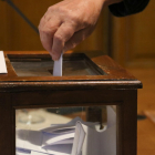 Imagen de detalle de uno de los votantes depositando su voto en la urna.