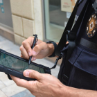 Un agente con una tableta electrónica realizando un trámite a pie de calle.
