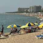 Banyistes parant el sol i entrant a l'aigua a la platja de Blanes.