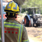 Un bomber mirant el tractor calcinat que ha provocat l'incendi a Mont-roig del Camp.