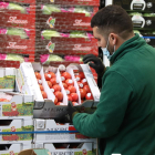 Un treballador col·locant producte a una de les parades de fruites i verdures.