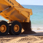 Un camión vertiendo arena en la playa de Altafulla.