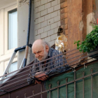 Persona d'edat avançada mirant el carrer des d'un balcó.