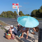 Usuaris de l'EMT esperant l'arribada del bus sota un paraigues.