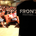 Logo del festival FRONT en la samarreta d'un col·laborador a les portes de l'auditori de Tortosa amb alumnes veient un documental.