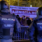 Dos agentes de policía custodian la sede del PSOE en la calle Ferraz de Madrid frente a manifestantes con una pancarta contraria a la amnistía.