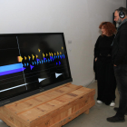 Dos espectadors escolten l'obra 'Contorns', en el marc de l'exposició 'FORMS - música visual generativa' a Lo Pati - Centre d'Art de les Terres de l'Ebre.