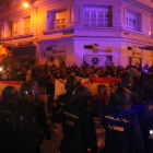 Manifestantes espanyolistas se encaran a policías nacionales antidisturbios detrás de banderas españolas.