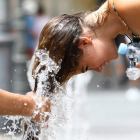 Una dona es refresca en una font per a combatre la calor.
