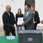 El director general de Memoria Democrática, Alfons Aragoneses, entrega la memoria de identificación de Narcís Mediavilla Cardó a sus nietos, frente a la caja que contiene los restos del soldado barcelonés.