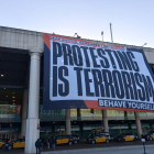 Òmnium desplega una pancarta gegant a l'aeroport del Prat amb el lema: 'A Espanya, protestar és terrorisme'