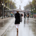 Una dona d'esquenes amb un paraigua caminant per la Rambla de Tarragona.